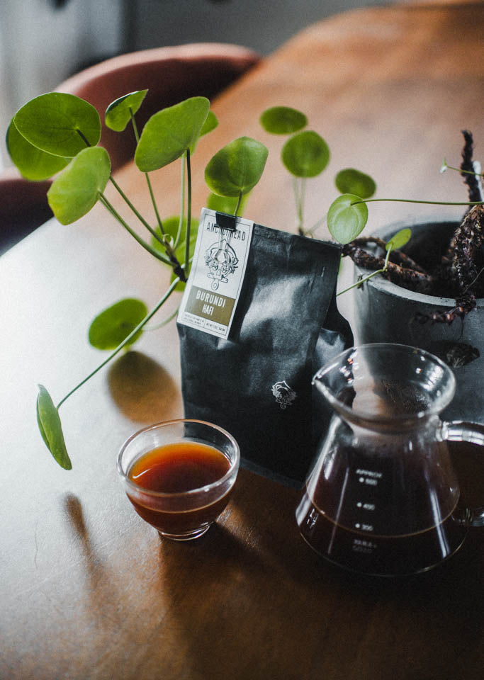 Coffee setup with a cup, carafe, and coffee bag on a wooden table.