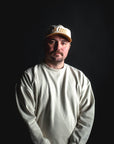 Man wearing a white cap and long-sleeve shirt against a black background