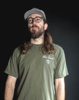 Man wearing a green t-shirt with 'Be Good' text on a dark background